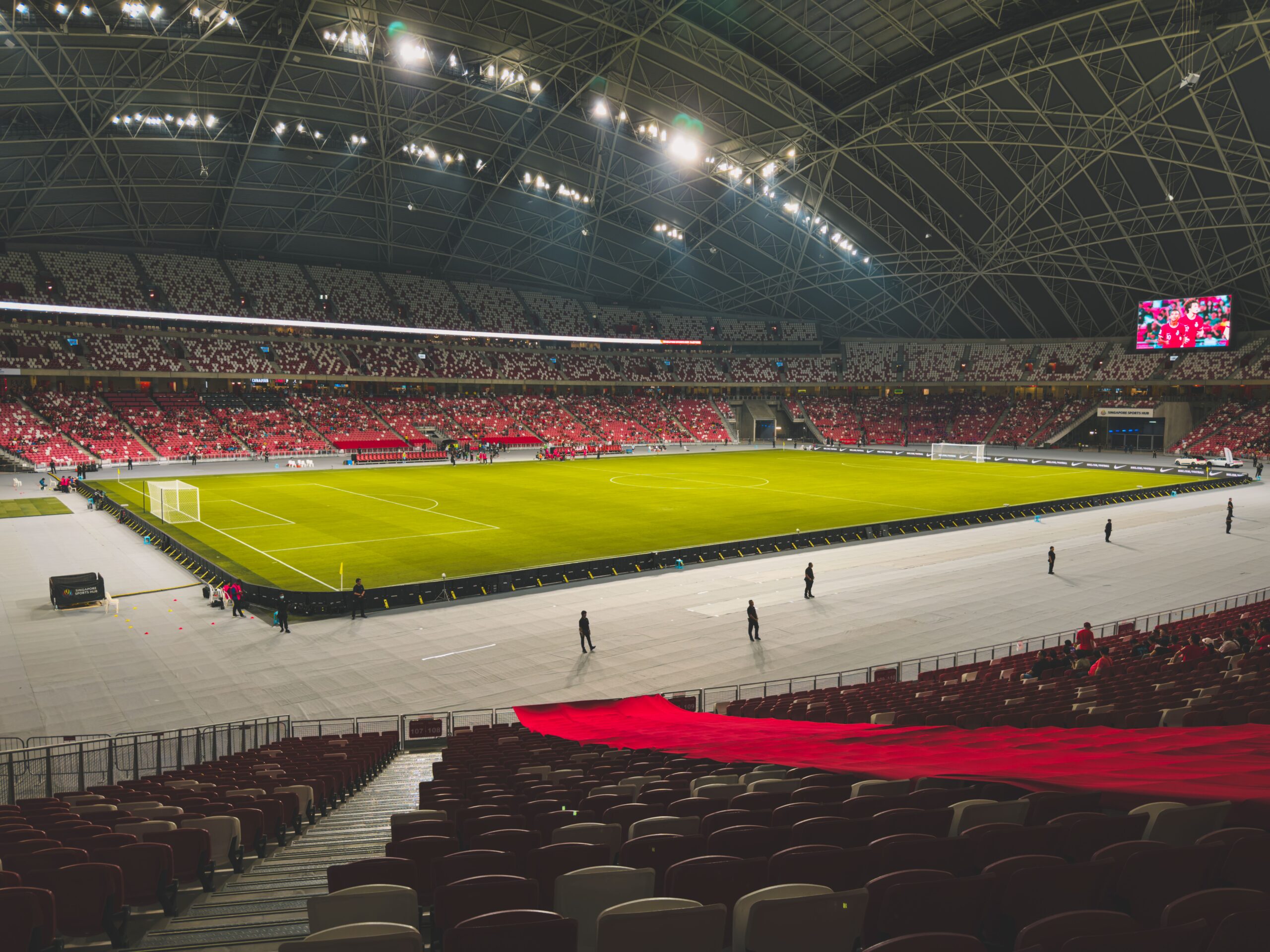 A breathtaking view of a massive modern sports stadium green field under bright bright floodlights during an international soccer event