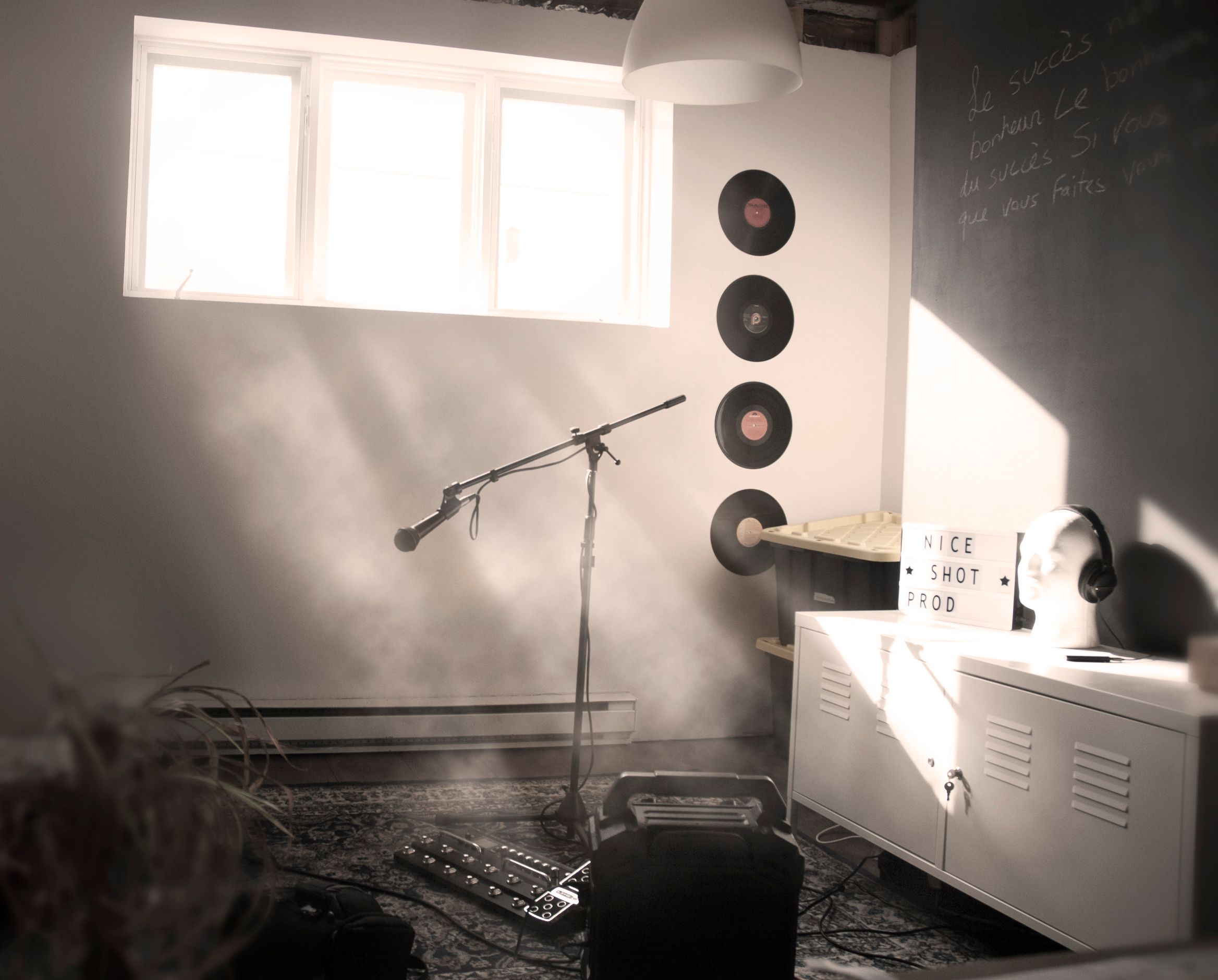 A professional music journalism photograph displaying a classic vintage metal studio microphone standing under soft, fading purple ambient spotlighting
