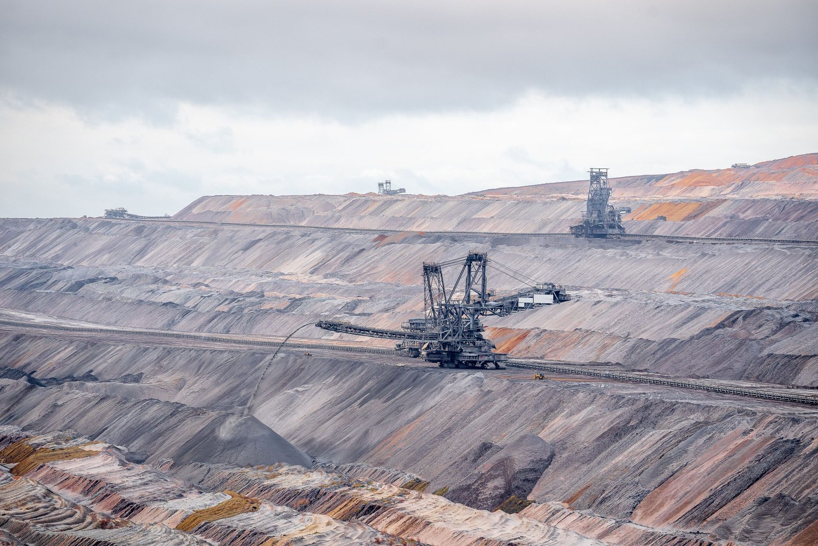 A vast open-pit mining operation showing heavy industrial haul trucks and copper extraction terrain.