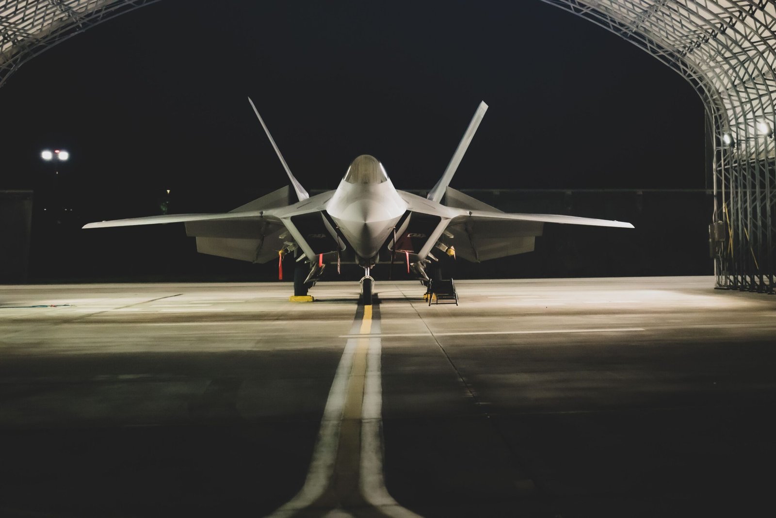 A high-tech military stealth fighter jet stationed inside a defense facility hangar.