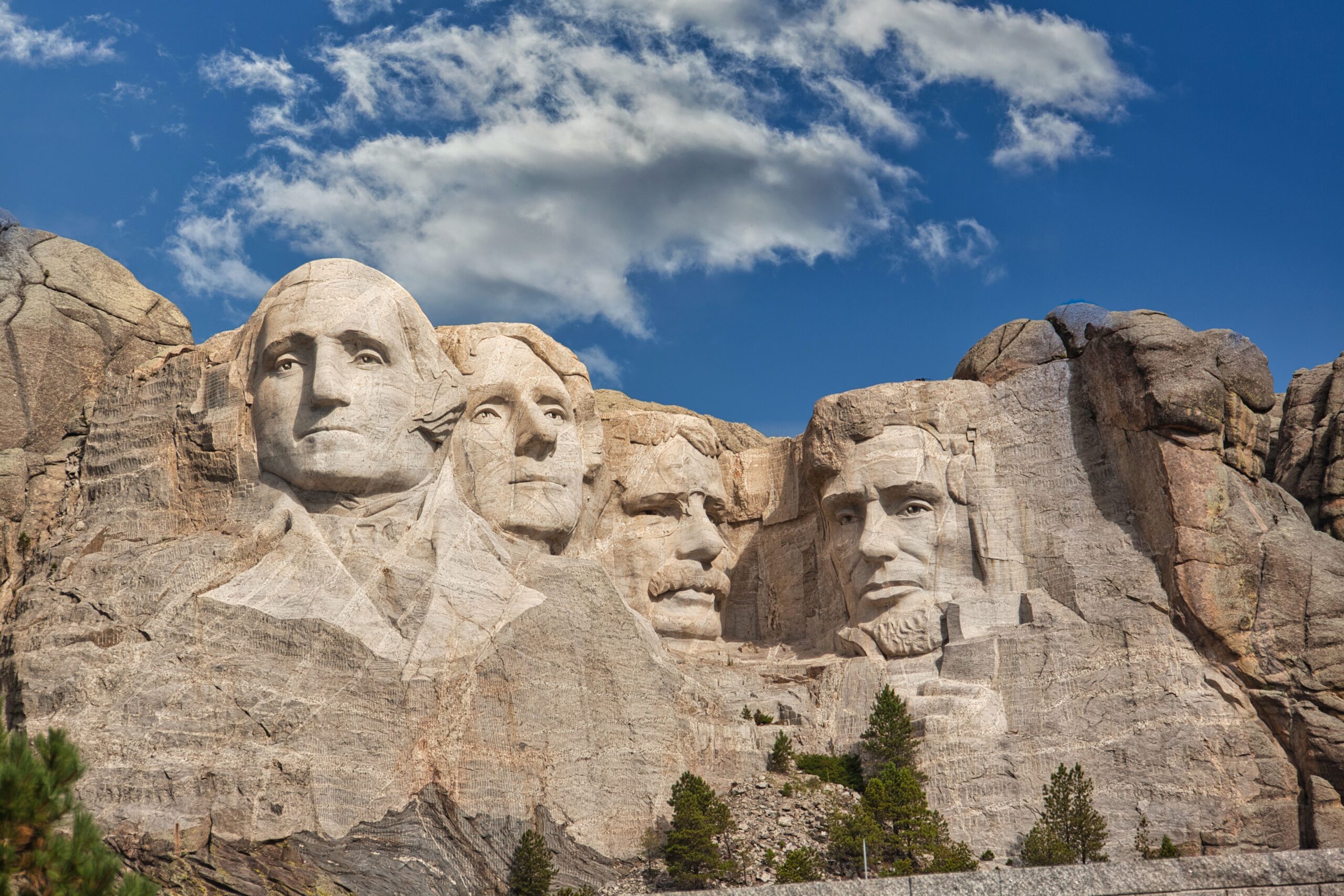 The historic Mount Rushmore National Memorial sculpted into the granite rock face under a clear blue sky