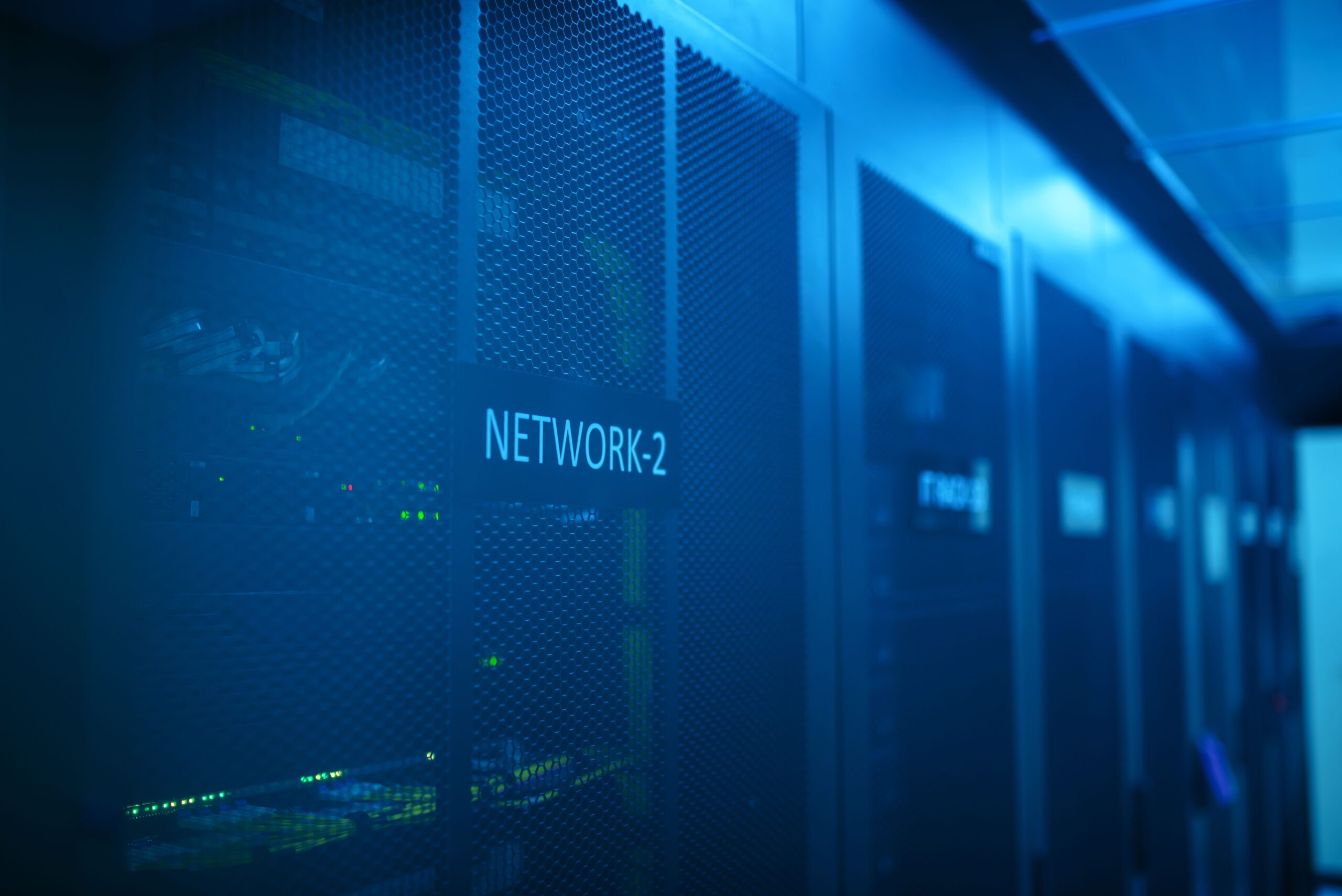 A professional photograph capturing clean rows of computer servers with blinking green and blue LED status indicators inside a data center