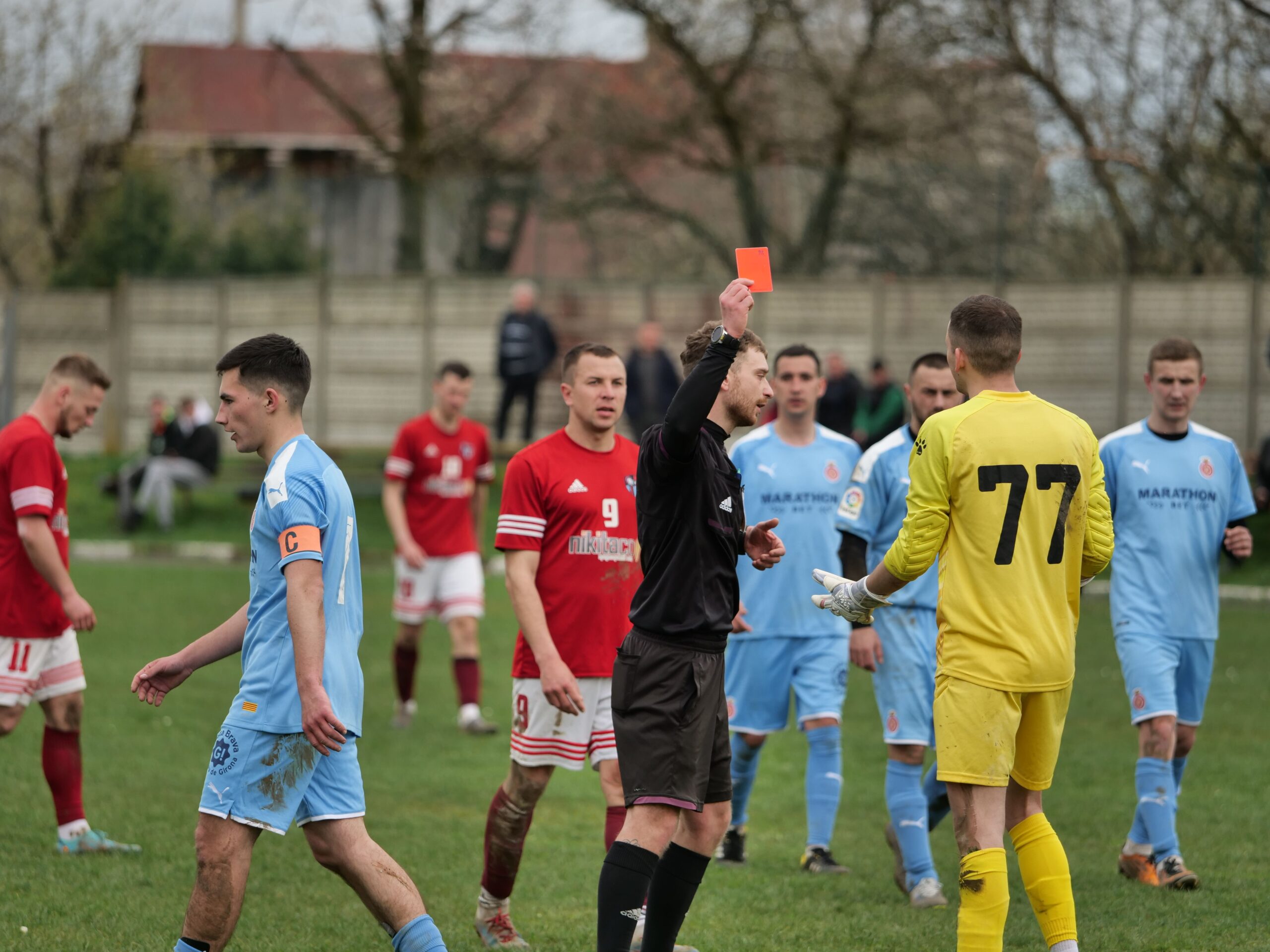 A professional yellow and red card resting on a green grass football pitch