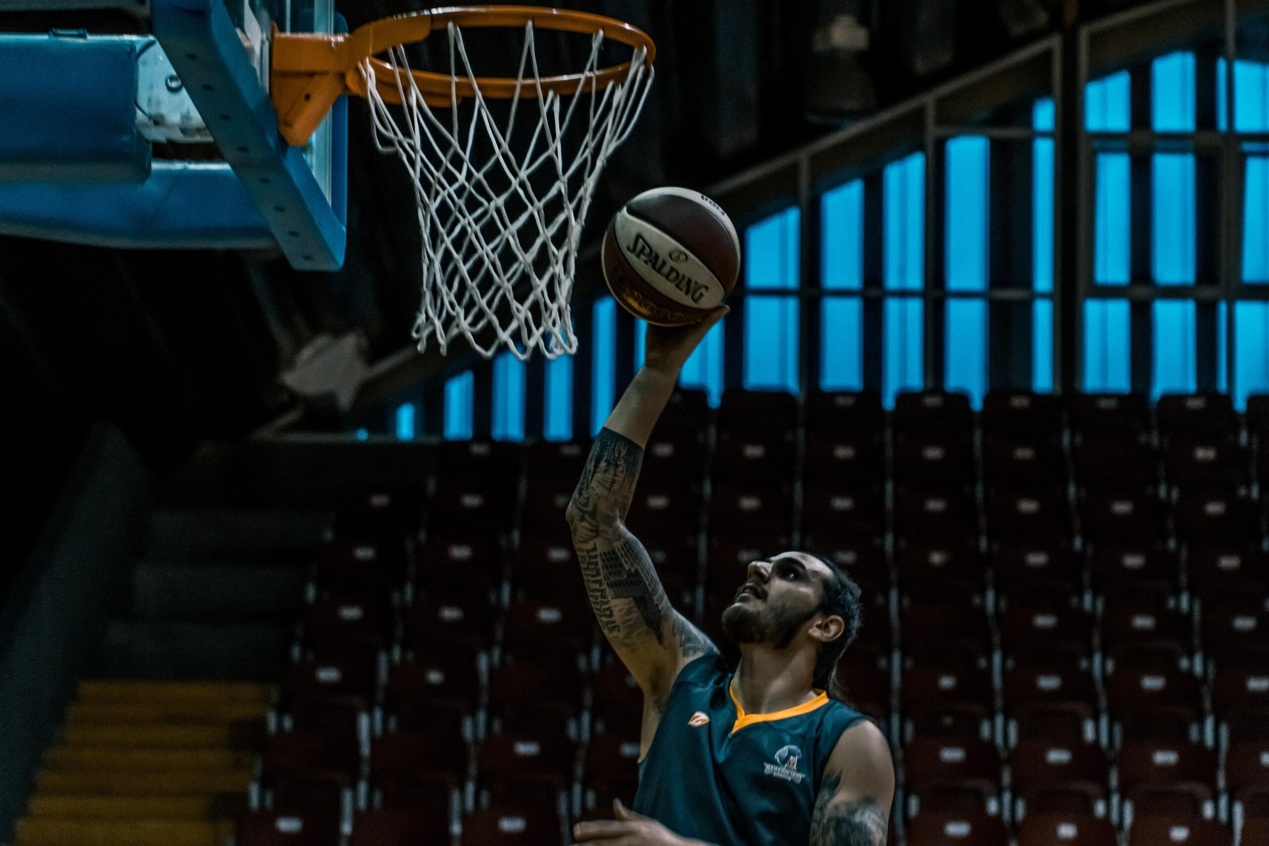 A professional sports journalism photograph capturing a polished, glossy indoor hardwood basketball court under bright, multi-angle stadium arena floodlights