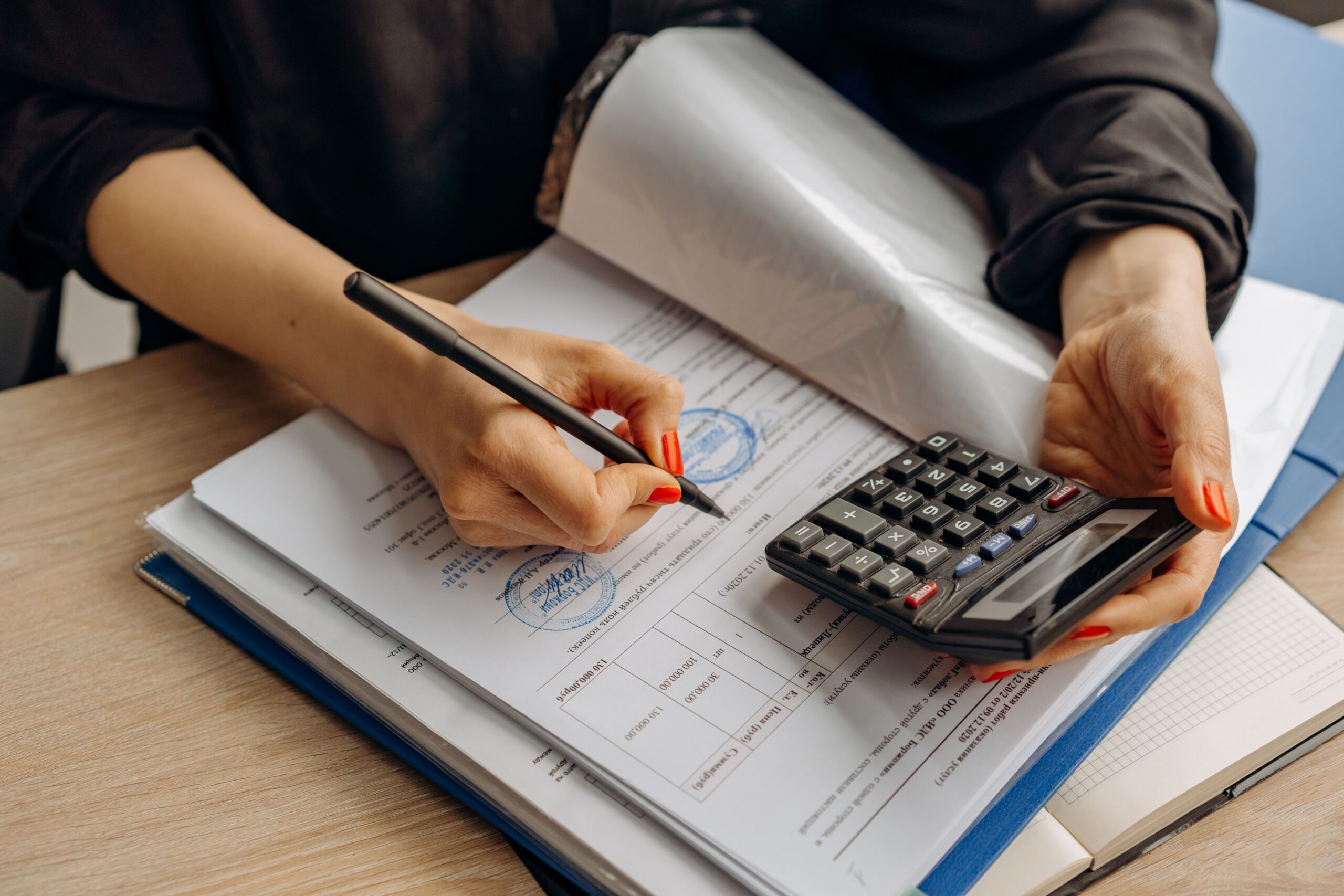 A professional accounting journalism photograph displaying neatly arranged federal tax documents and a modern digital calculator on a polished workspace