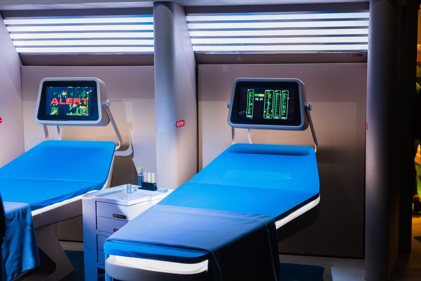 A professional medical journalism photograph showcasing a futuristic automated hospital corridor with blue digital telemetry interfaces representing New York nurses replaced by AI frameworks