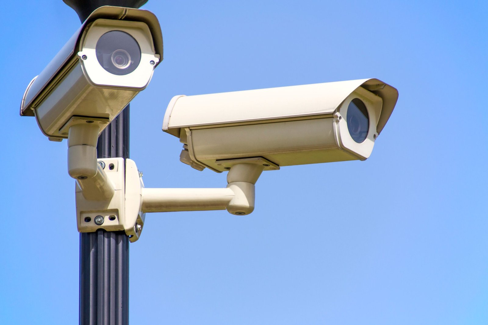 A high-tech black surveillance camera mounted on a city pole tracking street traffic.