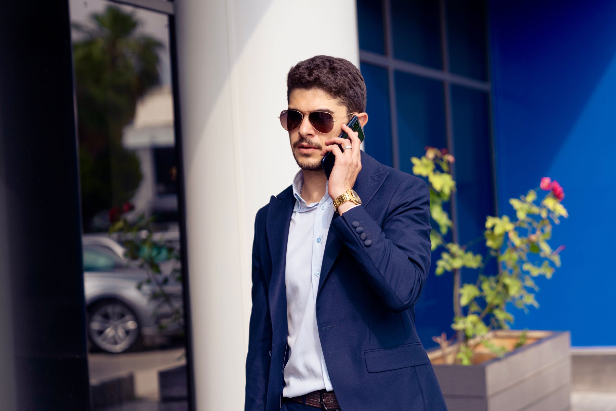 A professional security detail agent wearing a dark suit and earpiece standing guard outside a stately estate