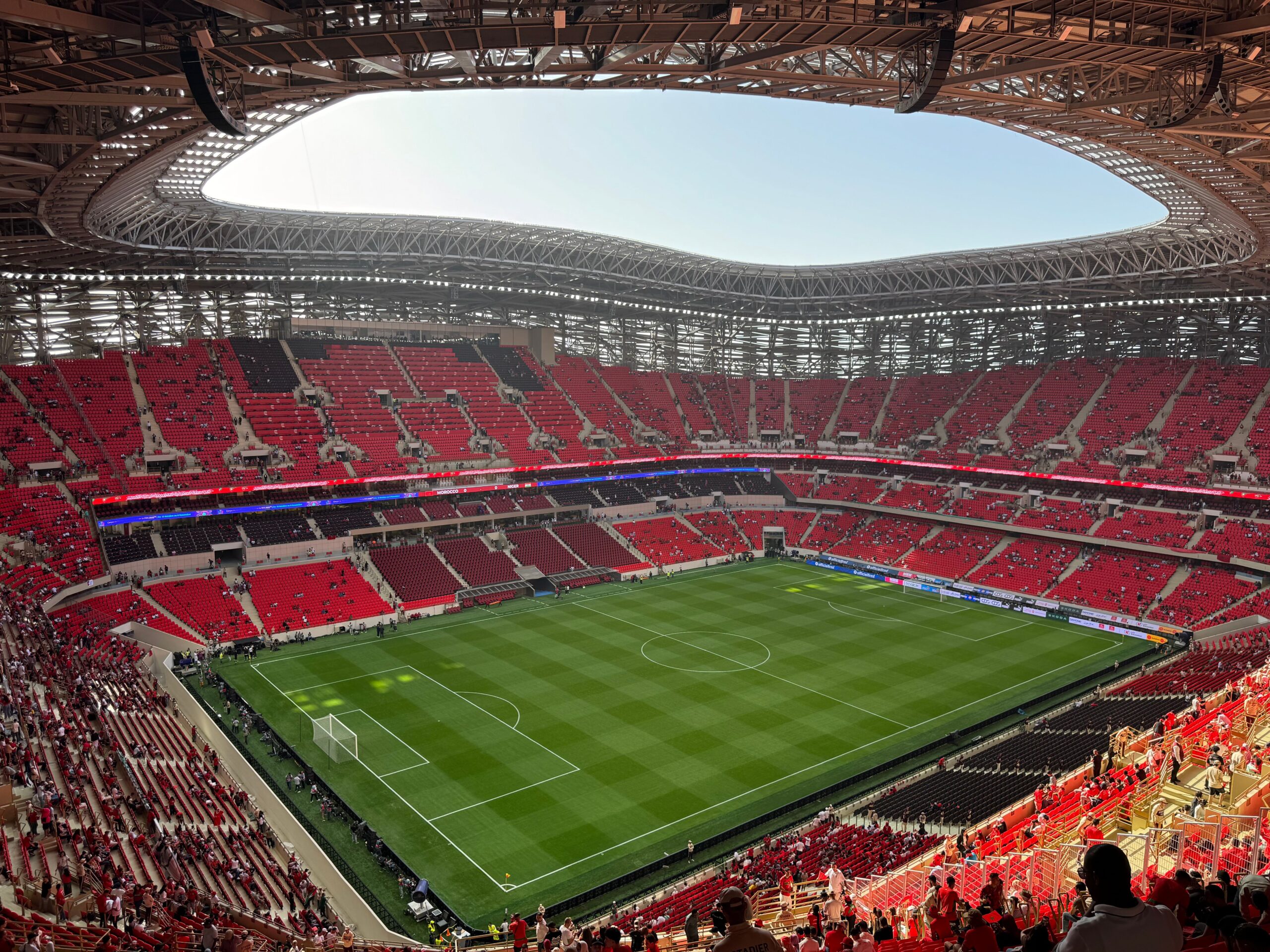 A modern stadium football pitch with international flags representing Senegal vs Belgium knockout match