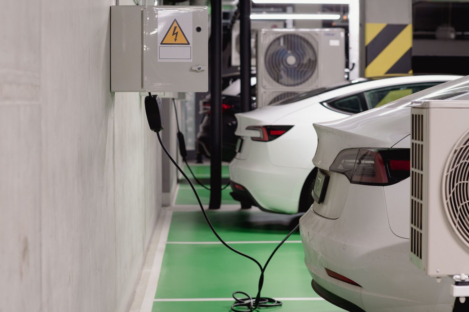 A professional modern side profile photograph of a sleek electric vehicle parked under an advanced charging infrastructure array.