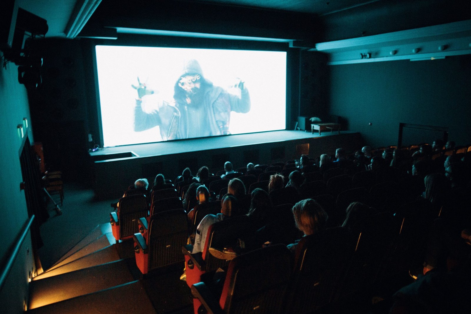 A professional deep-focus photograph inside a massive modern cinema hall with glowing ambient lighting focused on a large projection display structure.
