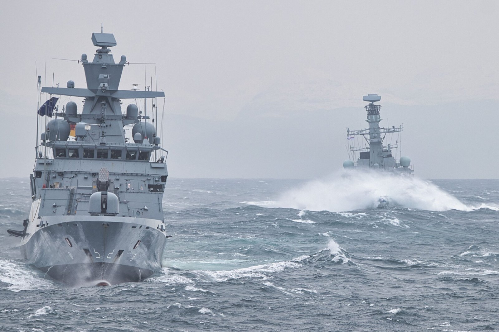 A professional geopolitical journalism photograph capturing an advanced naval warfare carrier group performing tactical maneuvers representing how Trump reinstates Iranian port blockade measures