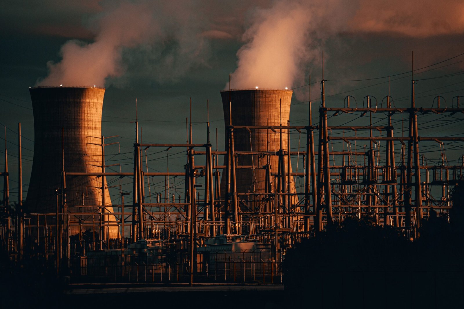 A professional global logistics journalism photograph capturing heavy electrical transmission lines and power station layouts representing how the Trump threatens strikes on Iranian infrastructure telemetry develops