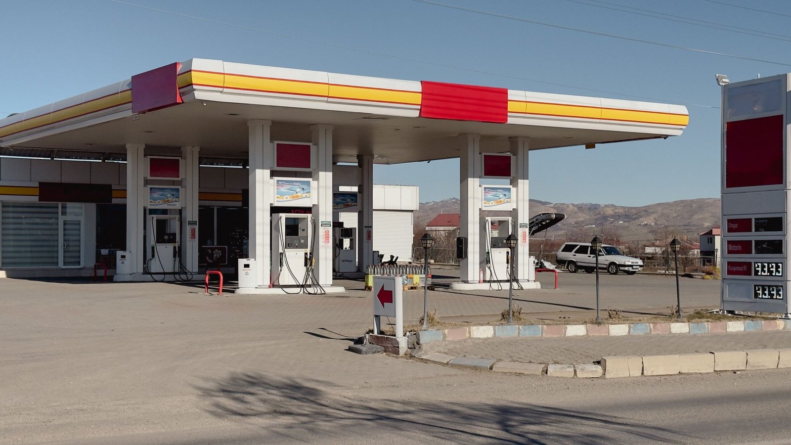 A close-up shot of a fuel nozzle at a gas station pump with digital price displays.