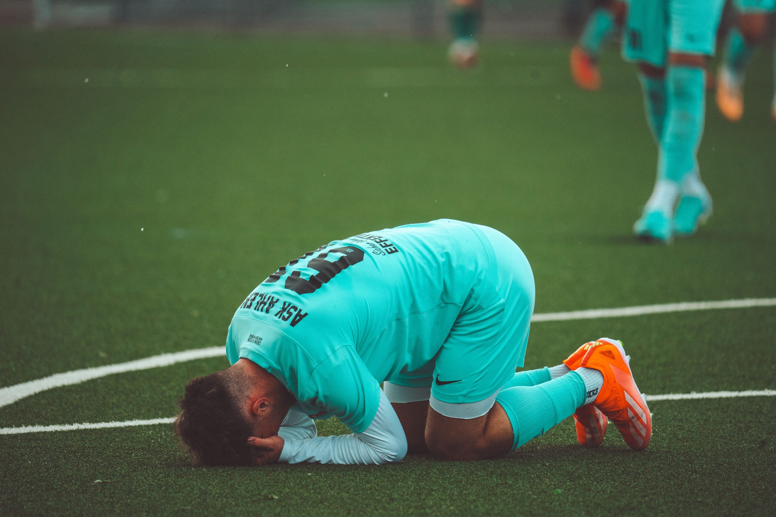 A professional sports photograph capturing the emotional distress of soccer players standing on a stadium pitch after a major tournament defeat
