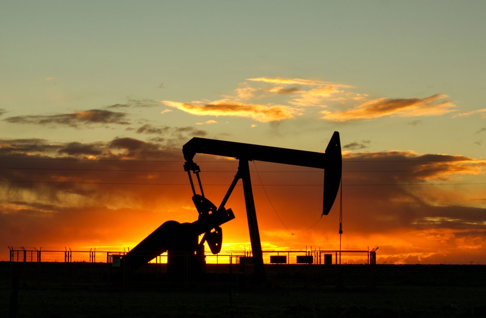 A professional financial journalism photograph capturing mechanical petroleum extraction rigs representing how the Vitol VTX Energy Partners divestment executes