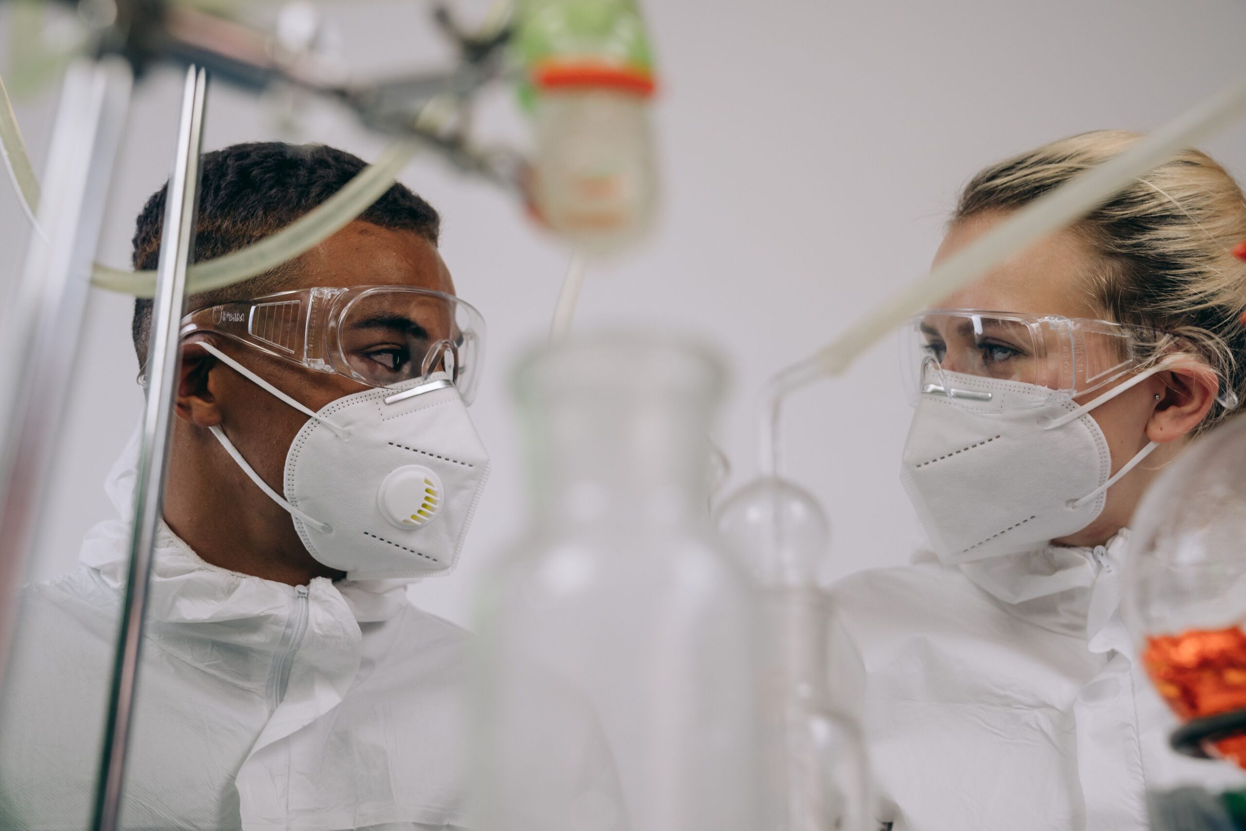 A medical doctor holding a syringe vial next to a microscope inside a healthcare laboratory facility