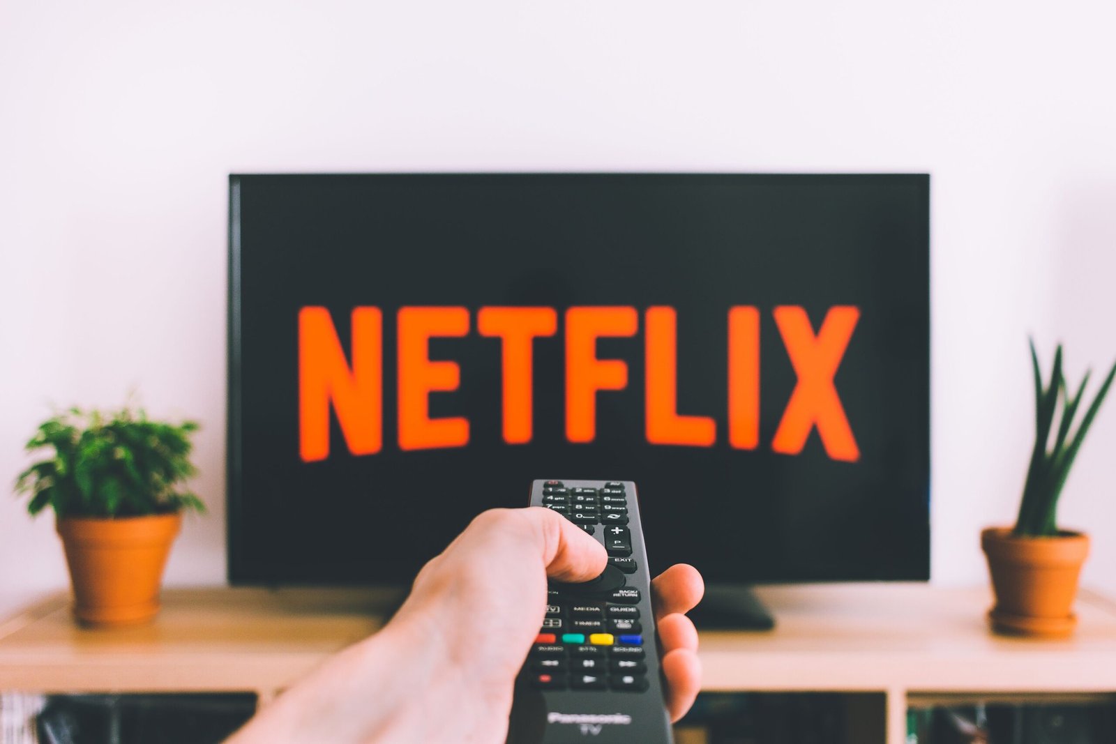 A person holding a remote control looking at a Netflix streaming interface with price hike and cancellation icons